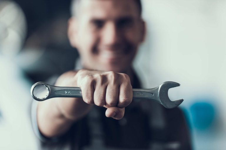 Mechaniker für Reparatur und Wartung bei TOP Markenspezialist [dealer_name], Spezialist für [dealer_brands]. Mechaniker schiebt Schraubenschlüssel vor